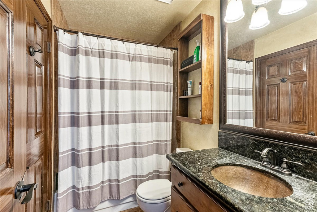 Bathroom featuring oversized vanity, a textured ceiling, and toilet