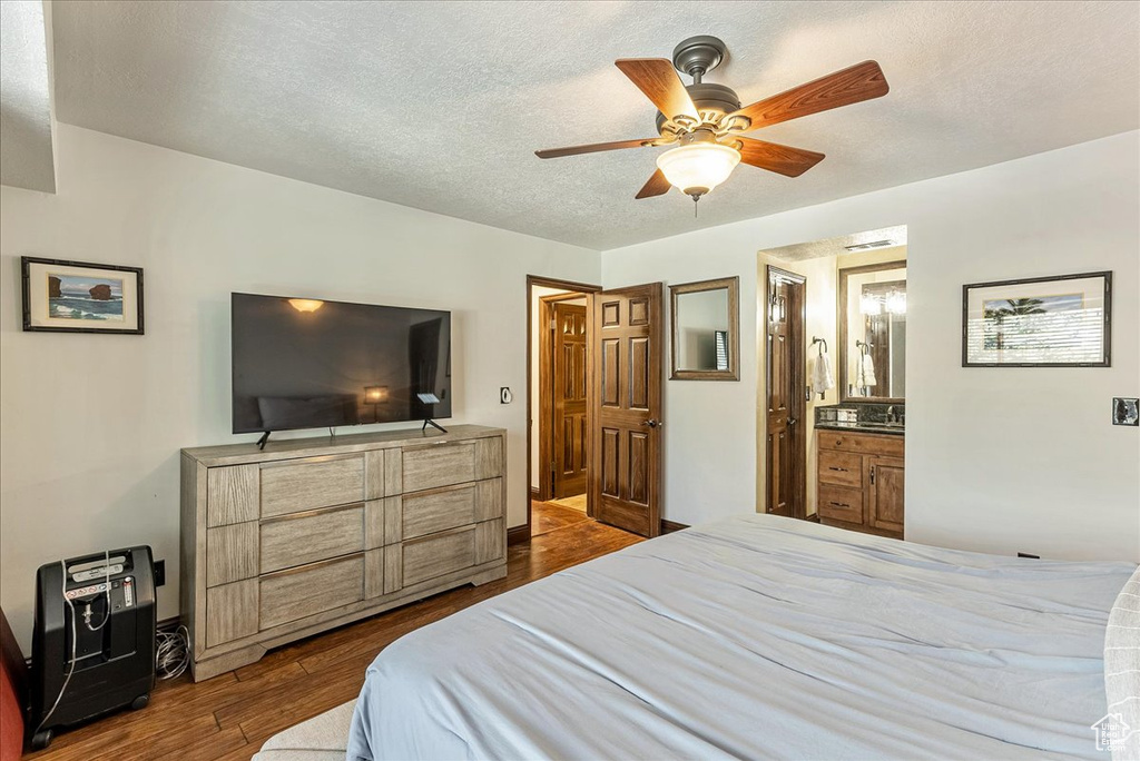 Bedroom with connected bathroom, a textured ceiling, ceiling fan, and dark hardwood / wood-style floors