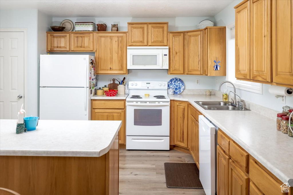 Kitchen with white appliances, light hardwood / wood-style flooring, and sink