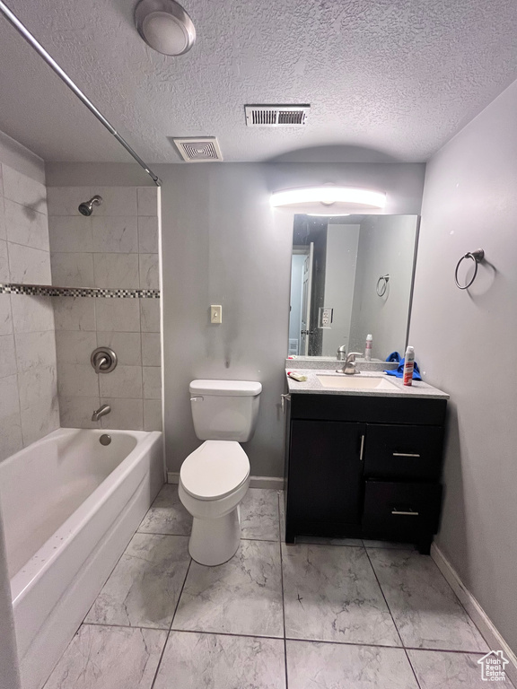 Full bathroom with oversized vanity, tiled shower / bath combo, tile floors, and toilet