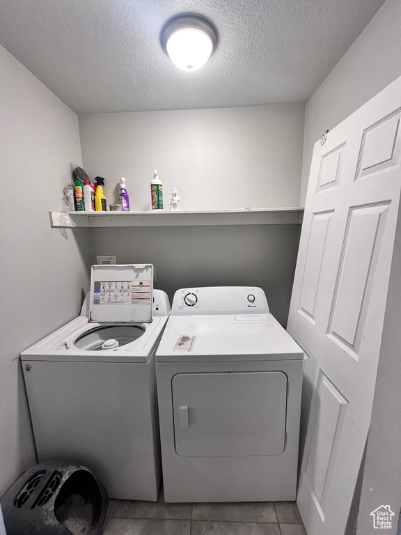 Laundry area with light tile floors, separate washer and dryer, and a textured ceiling