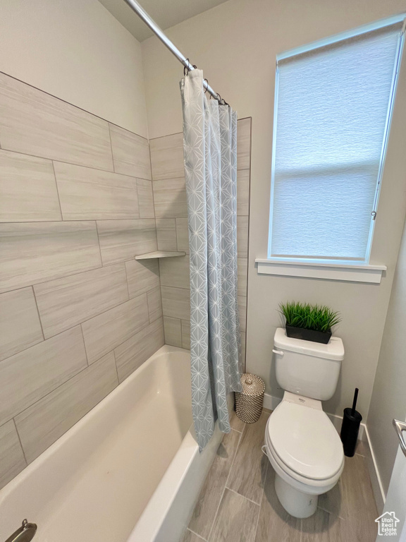 Bathroom with tile flooring, toilet, and shower / tub combo with curtain