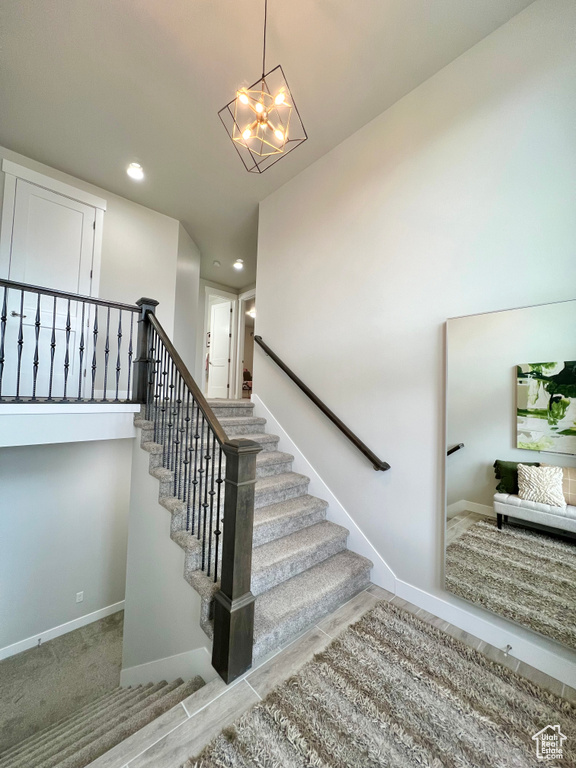 Stairs featuring an inviting chandelier and light carpet