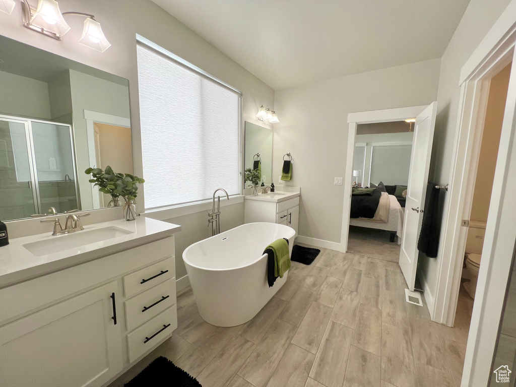 Bathroom featuring dual vanity, toilet, hardwood / wood-style floors, and a bath
