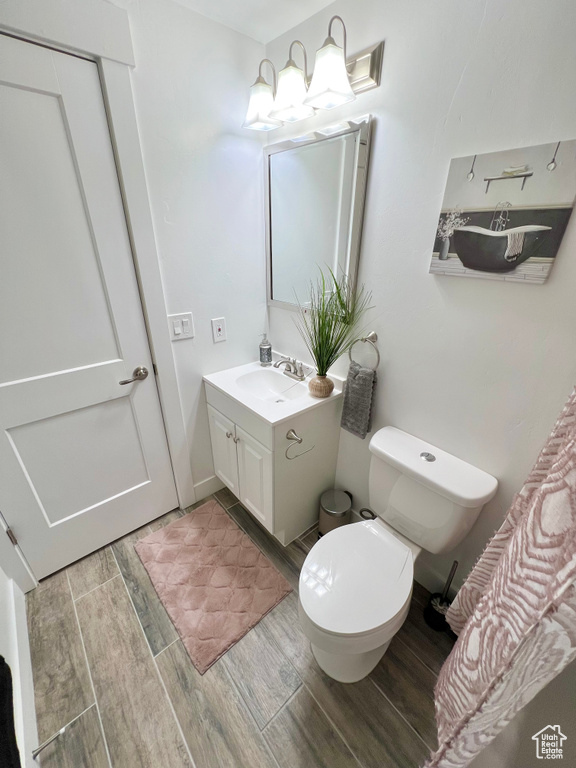 Bathroom featuring vanity with extensive cabinet space, hardwood / wood-style flooring, and toilet