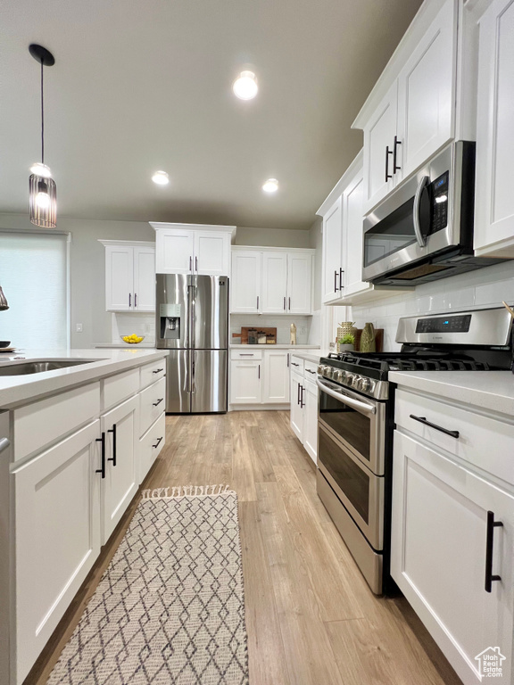 Kitchen featuring appliances with stainless steel finishes, light wood-type flooring, and white cabinetry
