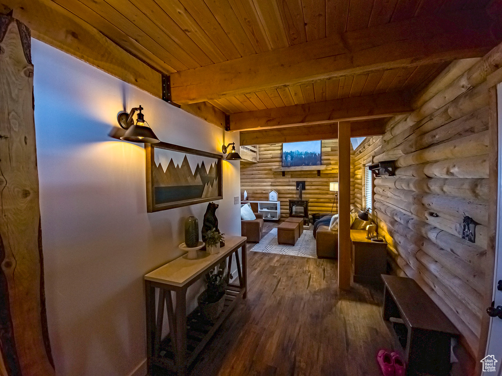 Hall with dark hardwood / wood-style flooring, rustic walls, beam ceiling, and wood ceiling