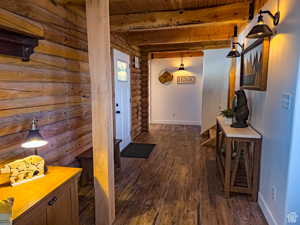 Interior space featuring dark wood-type flooring, log walls, wood ceiling, and beamed ceiling