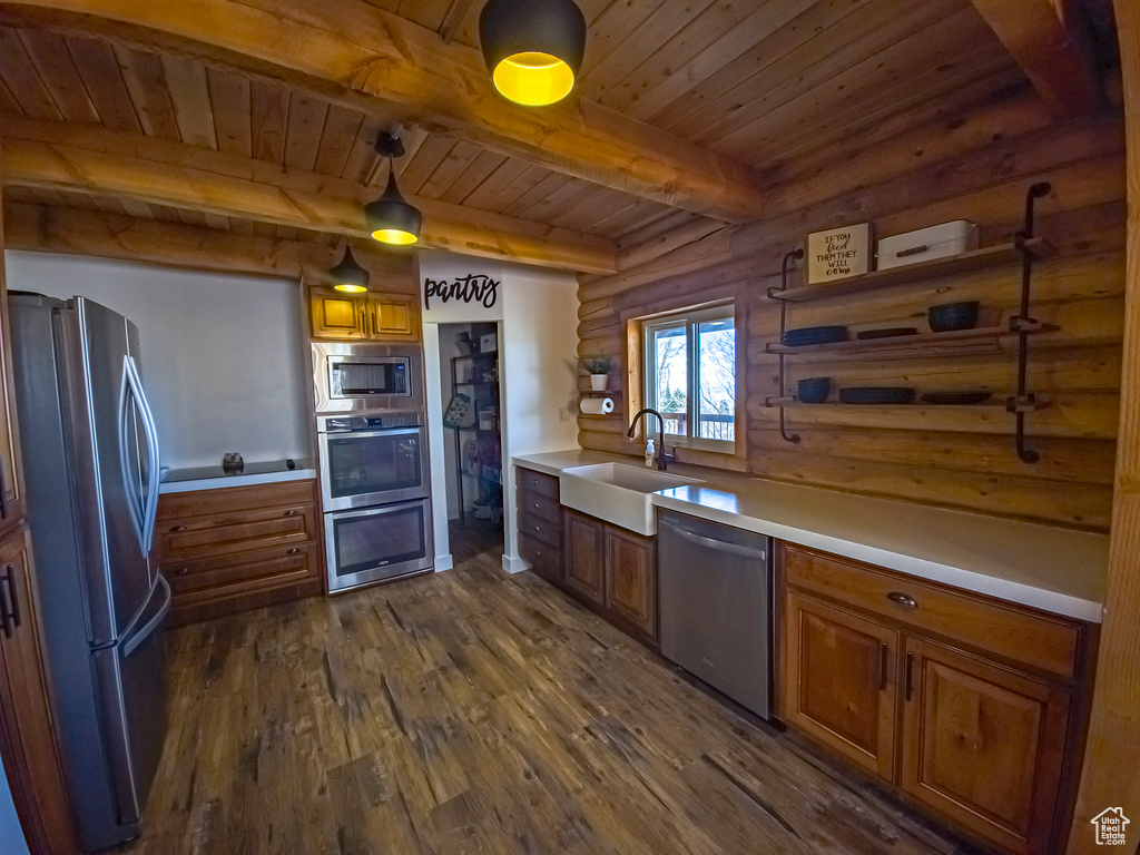 Kitchen with dark hardwood / wood-style flooring, beamed ceiling, sink, appliances with stainless steel finishes, and log walls