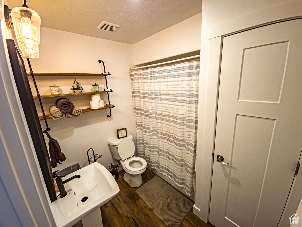 Bathroom featuring toilet, hardwood / wood-style flooring, a textured ceiling, and sink