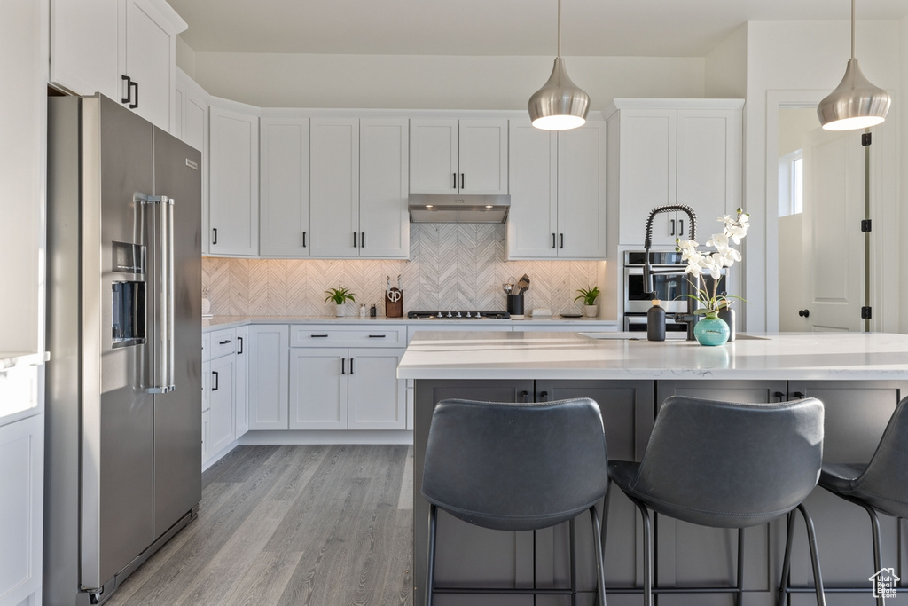 Kitchen with white cabinets, appliances with stainless steel finishes, and pendant lighting