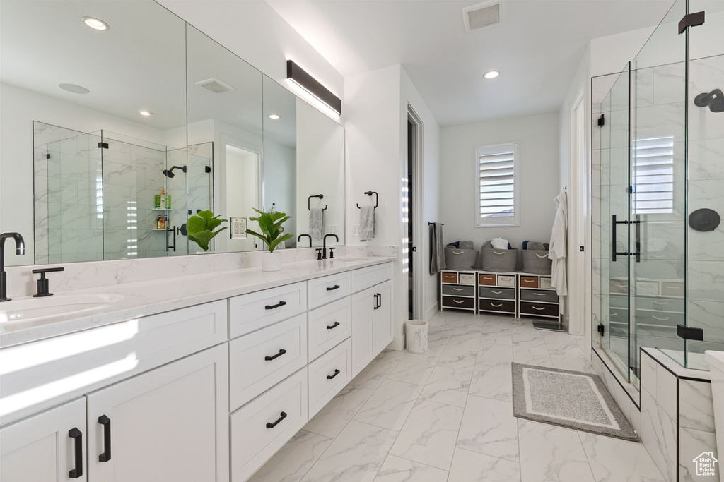 Bathroom featuring a shower with door, tile flooring, large vanity, and dual sinks