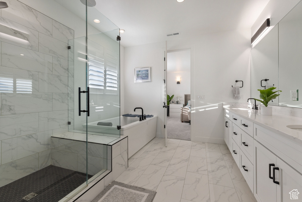 Bathroom with tile flooring, double sink vanity, and shower with separate bathtub