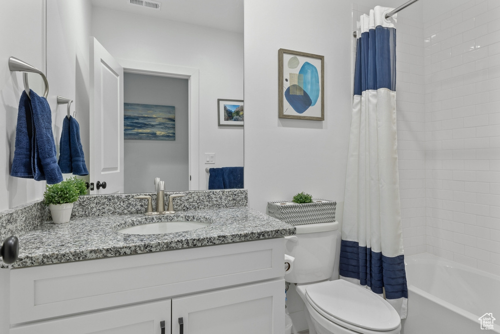 Full bathroom with toilet, vanity with extensive cabinet space, and shower / bathtub combination with curtain