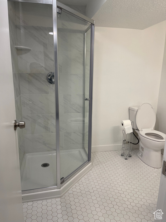 Bathroom featuring tile floors, a textured ceiling, toilet, and walk in shower