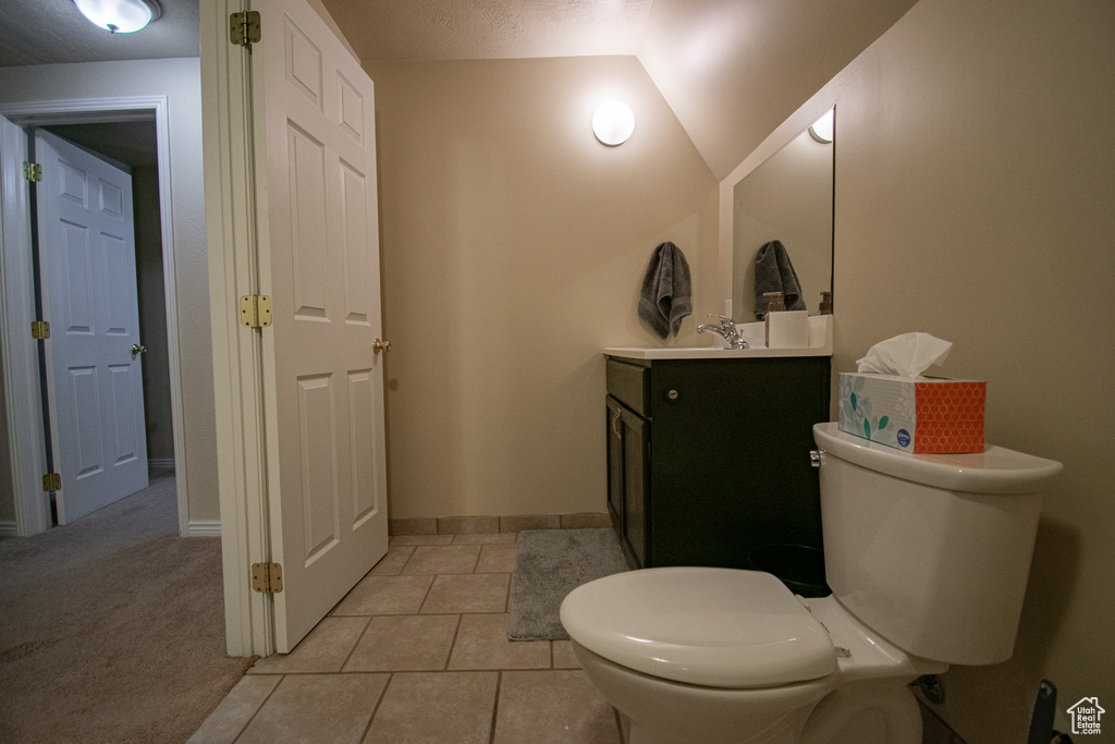 Bathroom with tile flooring, vaulted ceiling, toilet, and vanity