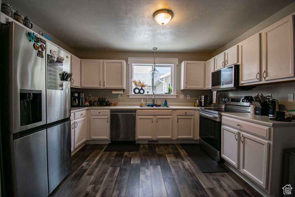 Kitchen featuring appliances with stainless steel finishes, dark hardwood / wood-style flooring, and white cabinets