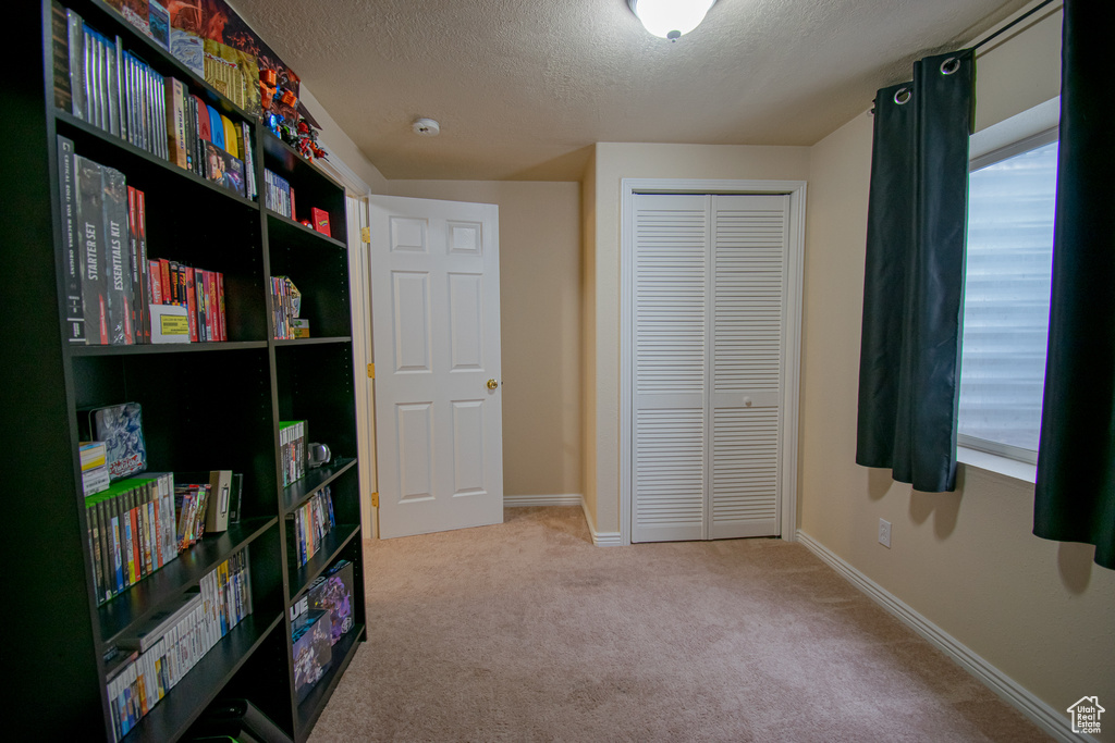 Bedroom with a textured ceiling, light carpet, and a closet