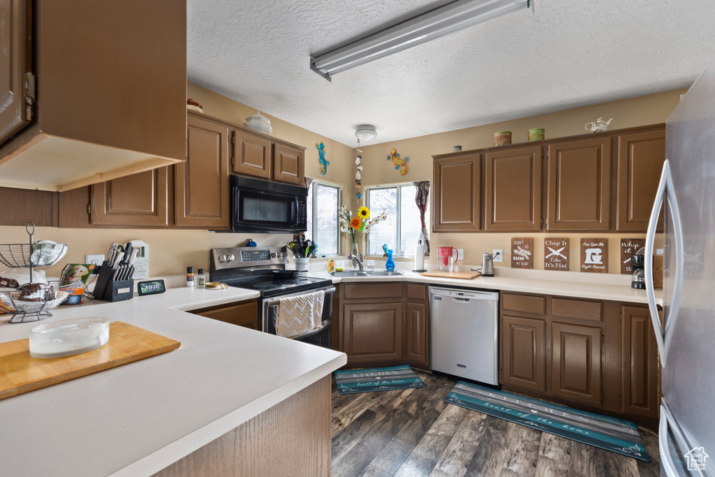 Kitchen featuring dishwashing machine, a textured ceiling, white fridge, dark hardwood / wood-style flooring, and electric range