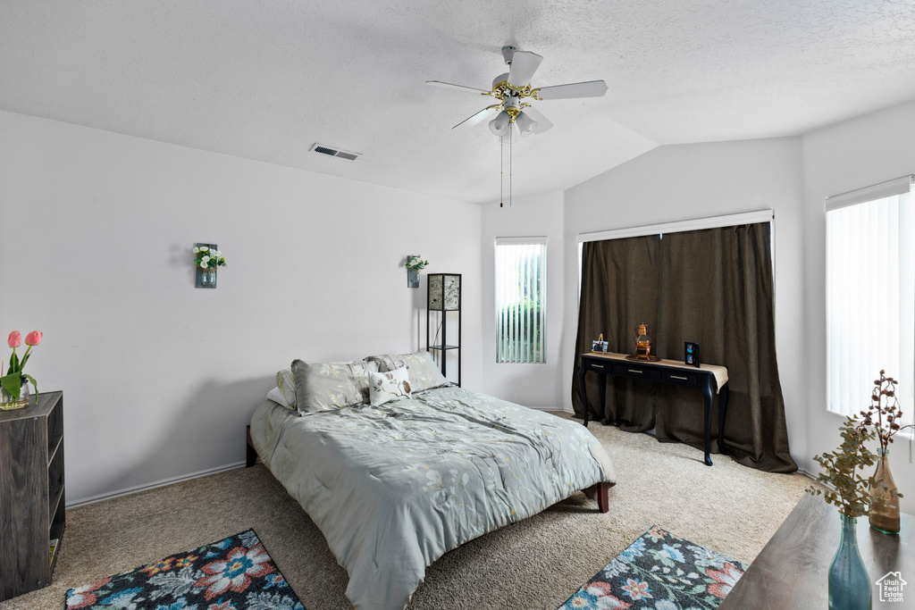 Bedroom featuring light colored carpet, a textured ceiling, vaulted ceiling, and ceiling fan