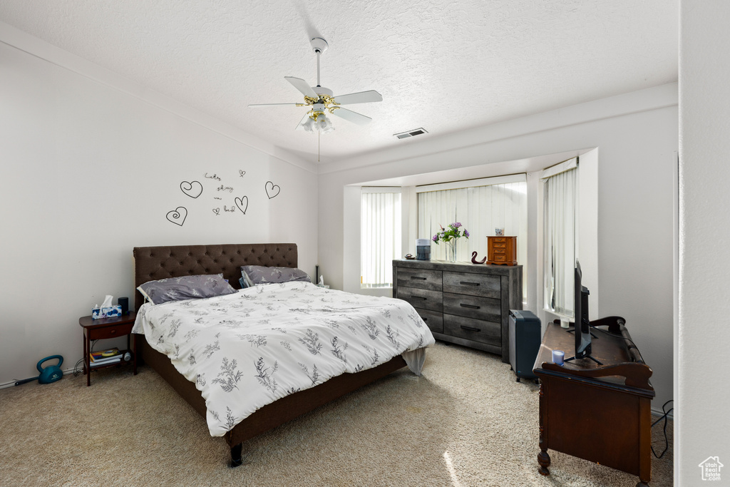 Bedroom featuring a textured ceiling, light carpet, and ceiling fan