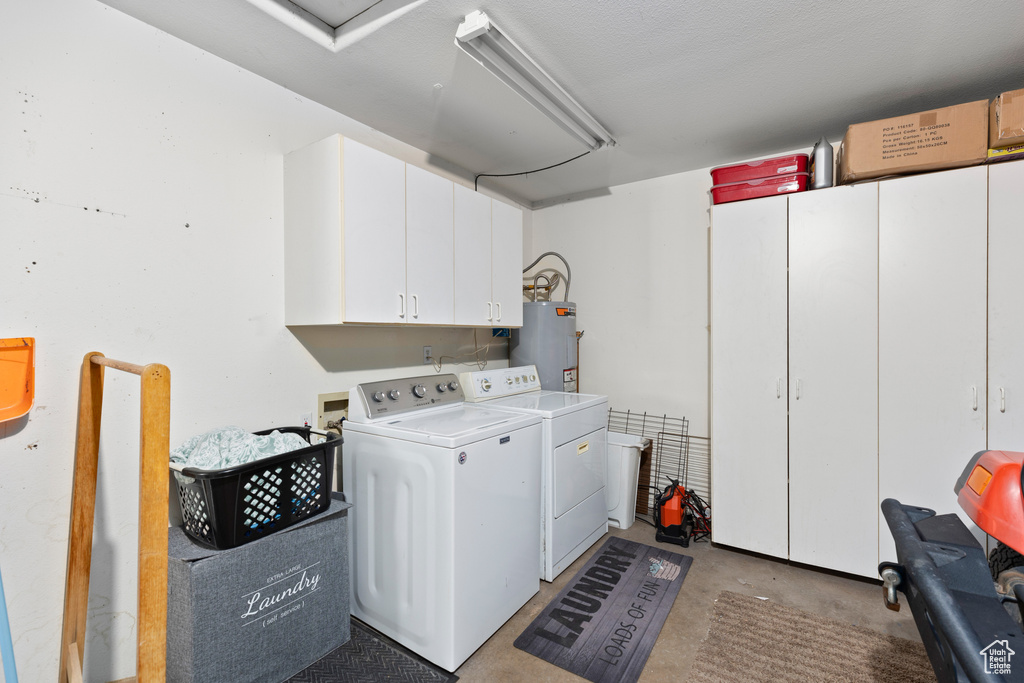 Laundry room with water heater, cabinets, washing machine and clothes dryer, and washer hookup
