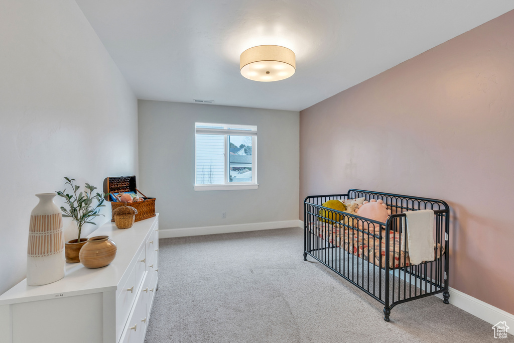 Bedroom with light carpet and a nursery area