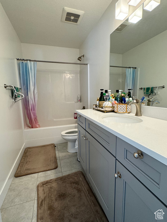 Full bathroom featuring tile floors, vanity, toilet, and shower / tub combo with curtain