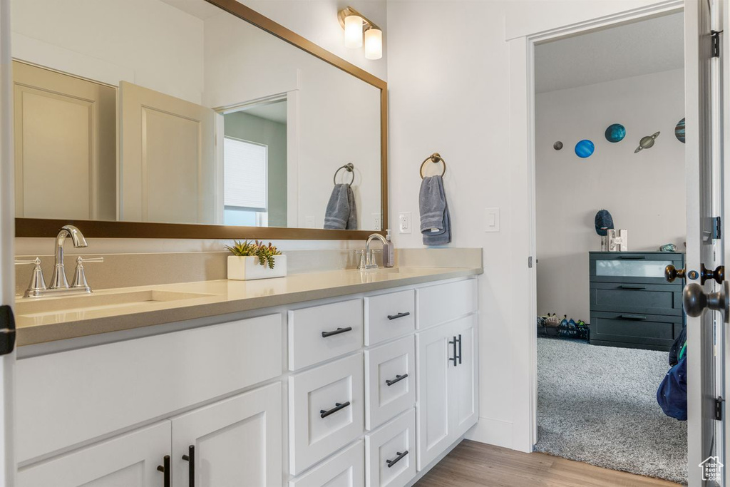 Bathroom with vanity with extensive cabinet space, hardwood / wood-style flooring, and double sink
