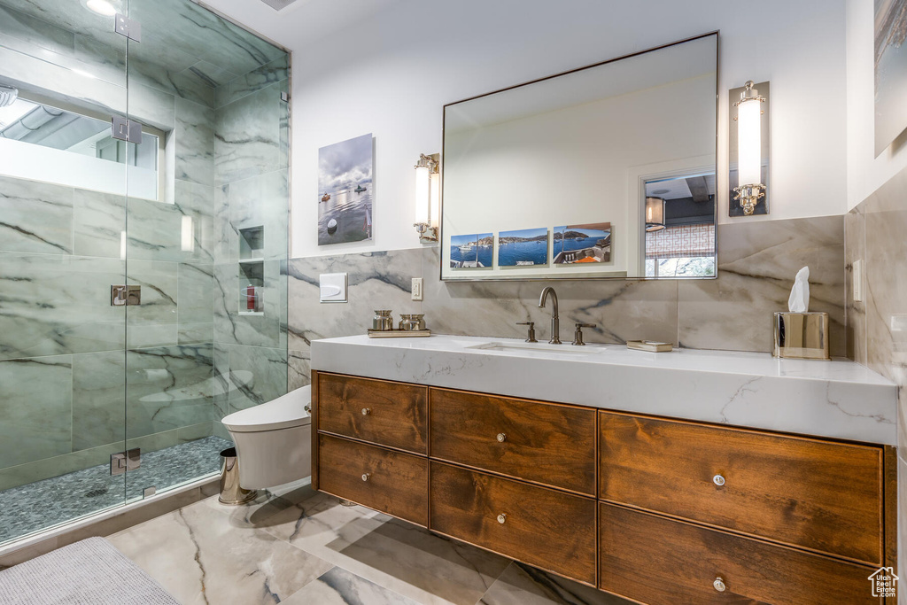 Bathroom with tasteful backsplash, oversized vanity, tile walls, tile floors, and toilet