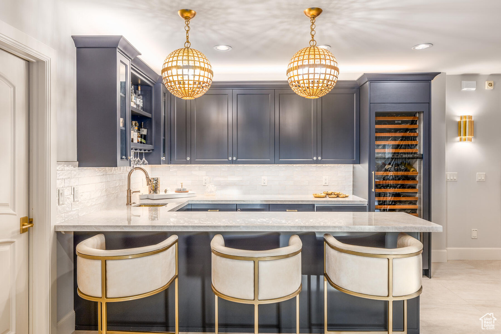 Kitchen featuring decorative light fixtures, sink, backsplash, and light tile flooring