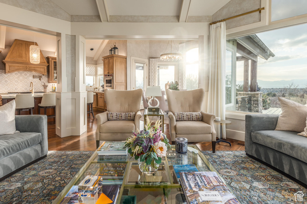 Living room featuring a notable chandelier, vaulted ceiling with beams, and dark hardwood / wood-style flooring