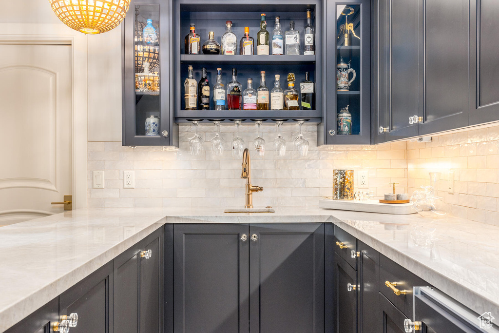 Bar featuring light stone countertops, sink, and tasteful backsplash