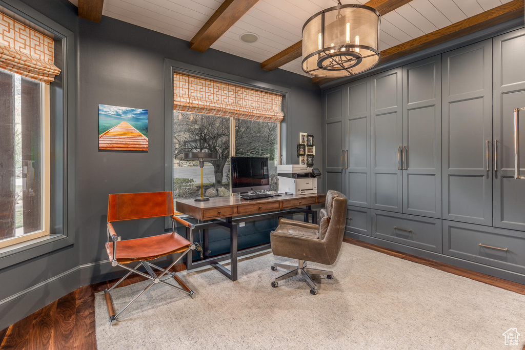 Home office featuring beam ceiling, an inviting chandelier, and hardwood / wood-style floors