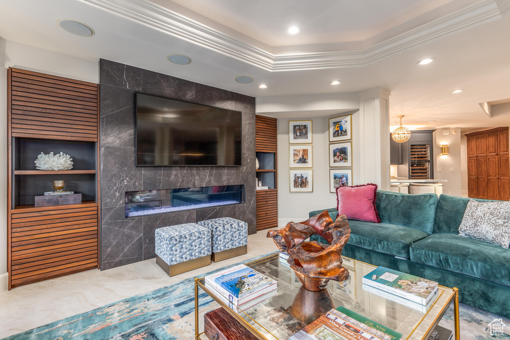 Living room featuring a tray ceiling, ornamental molding, built in shelves, and a fireplace