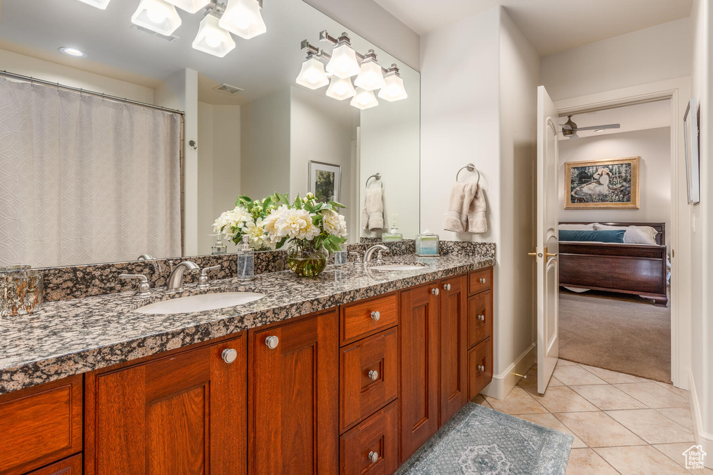 Bathroom featuring ceiling fan, oversized vanity, dual sinks, and tile floors