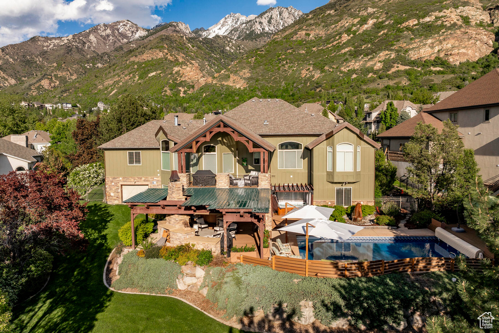 Rear view of house with a pool side deck with mountain view