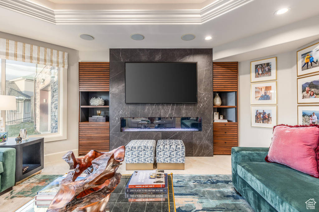 Tiled living room with a premium fireplace, built in shelves, and ornamental molding