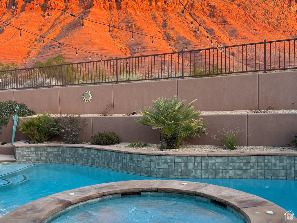 View of pool with a mountain view and an in ground hot tub