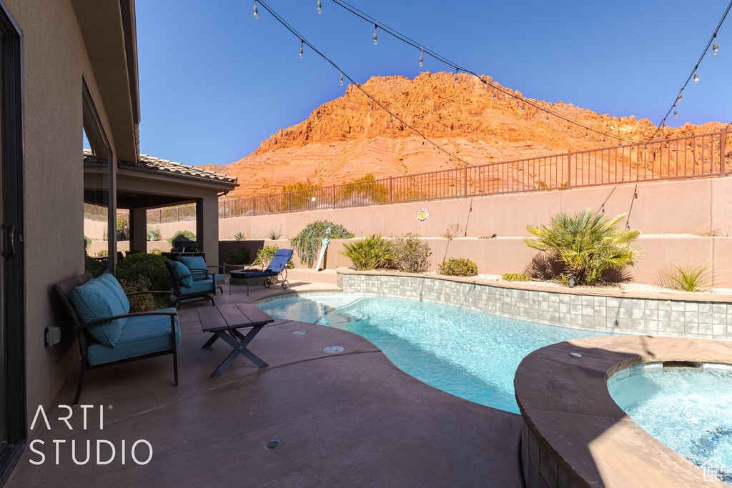 View of pool featuring an in ground hot tub, a patio area, and a mountain view