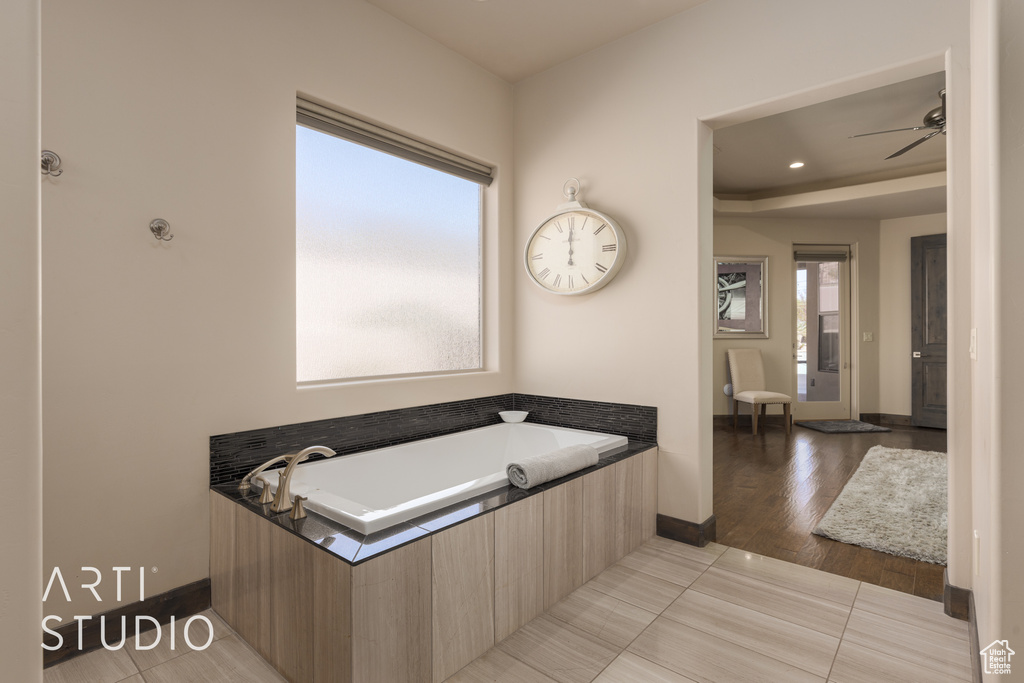 Bathroom featuring ceiling fan, wood-type flooring, and a bath