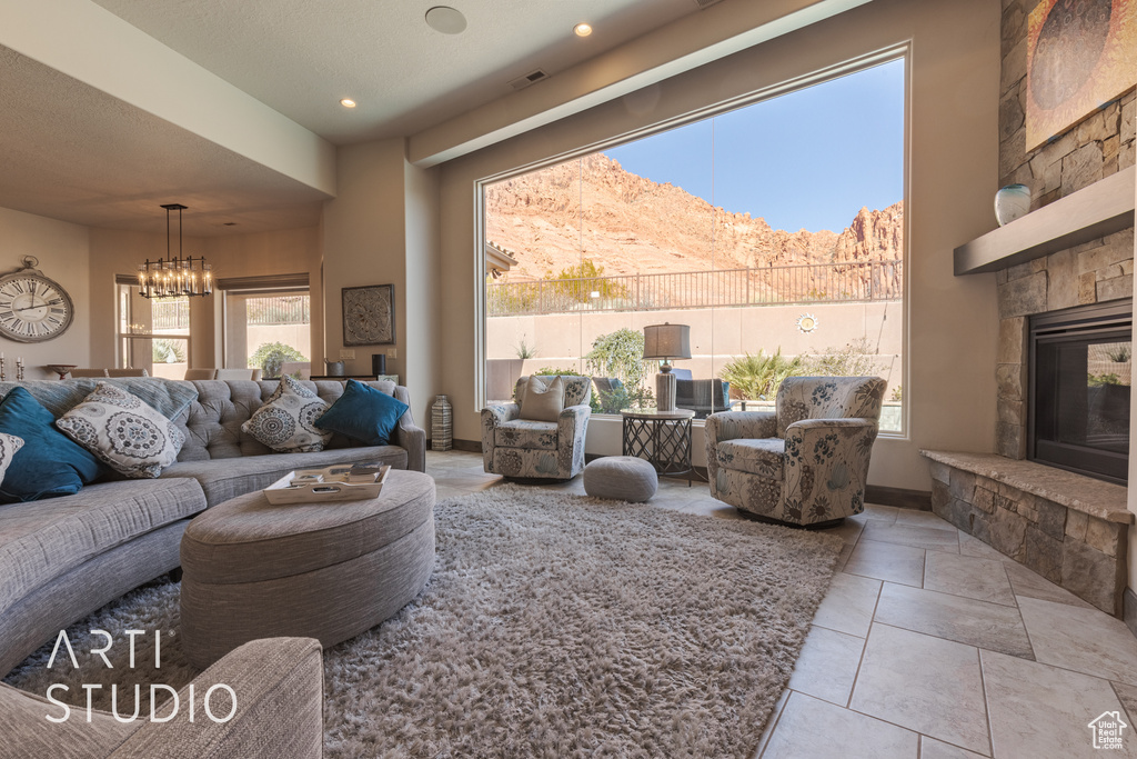 Living room featuring a chandelier, a stone fireplace, light tile floors, and a mountain view