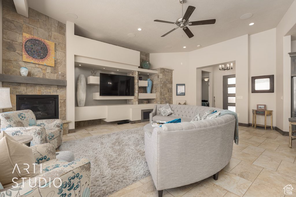 Living room featuring a large fireplace, light tile floors, and ceiling fan