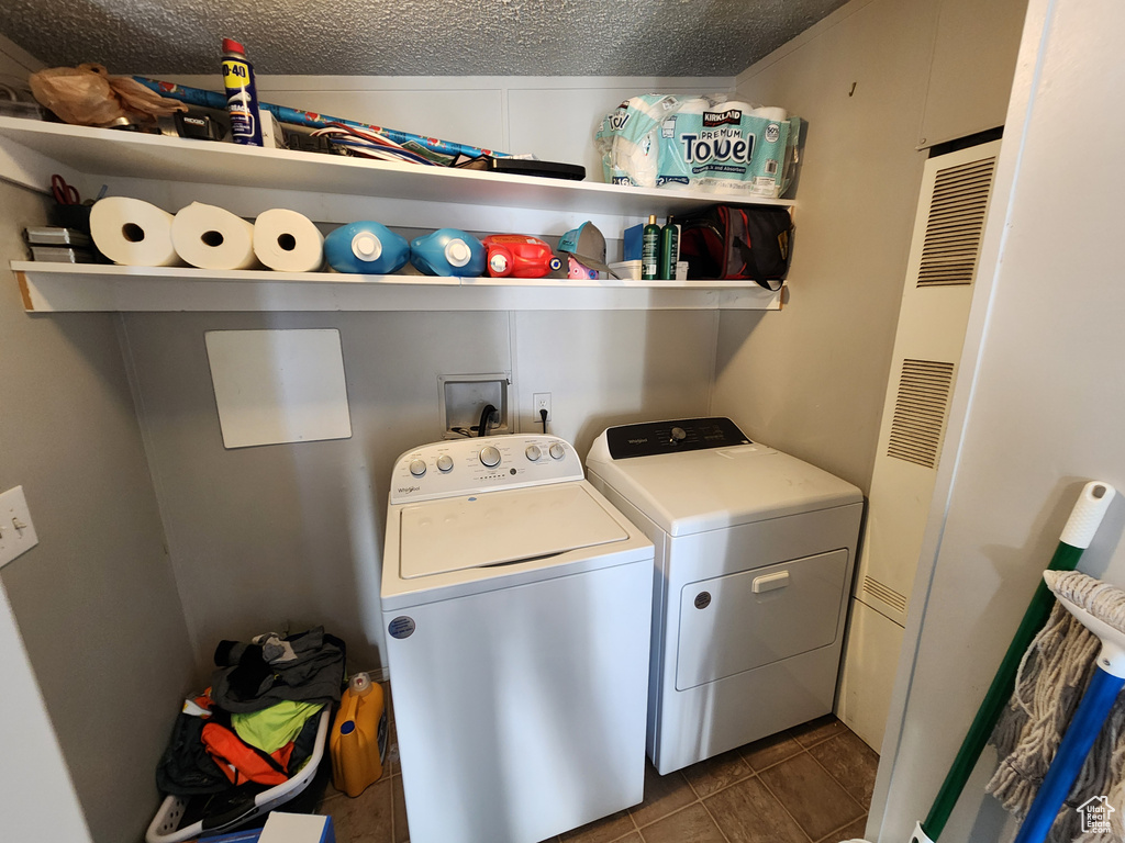 Clothes washing area featuring independent washer and dryer, a textured ceiling, washer hookup, and dark tile flooring