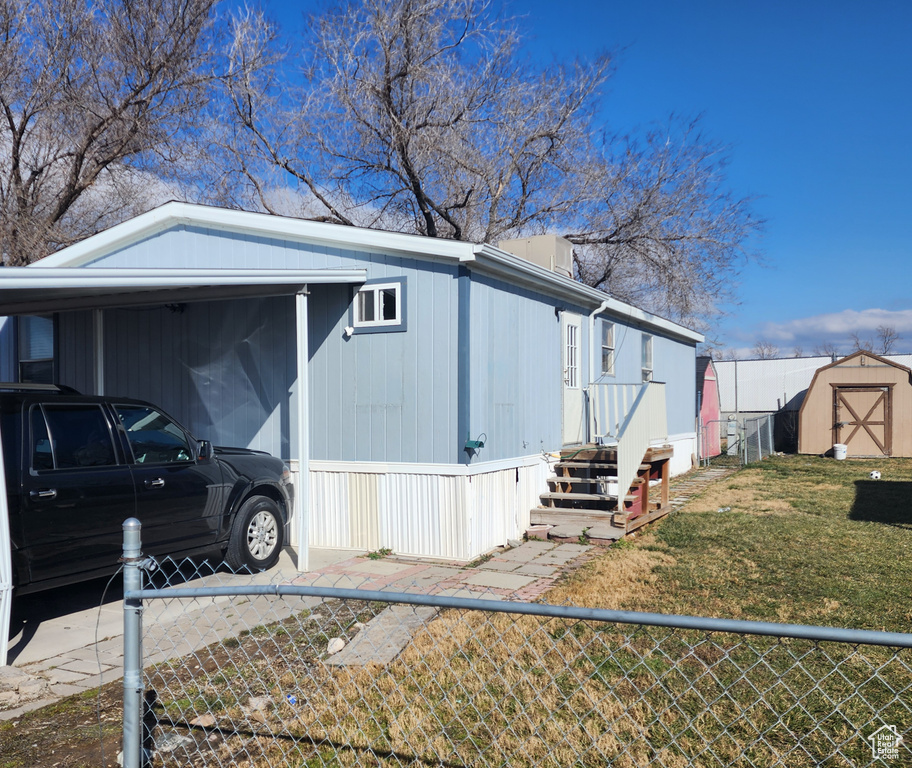 View of property exterior with a carport, a yard, and a storage shed