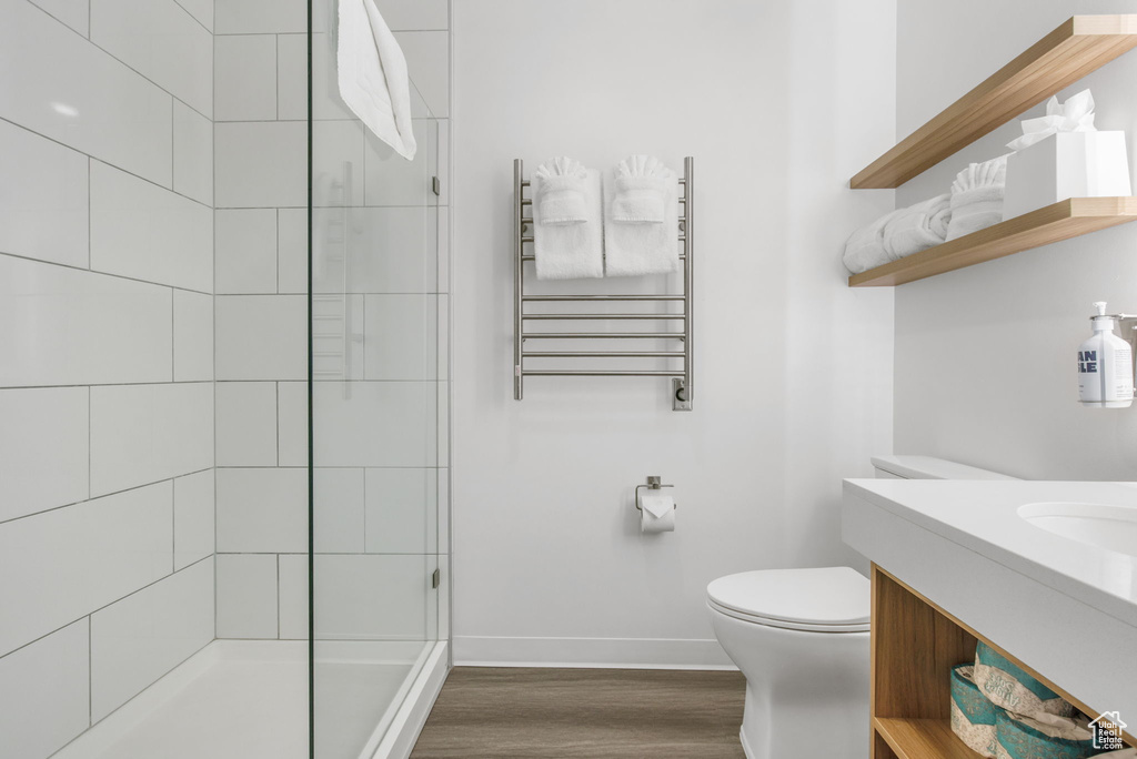 Bathroom with vanity, hardwood / wood-style flooring, radiator heating unit, toilet, and walk in shower