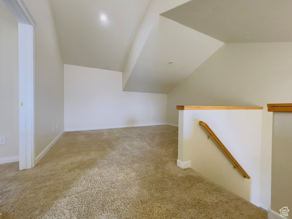 Additional living space with lofted ceiling and light carpet