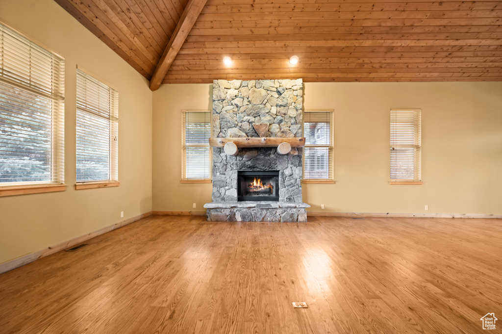 Unfurnished living room with vaulted ceiling with beams, a wealth of natural light, light hardwood / wood-style flooring, wood ceiling, and a fireplace
