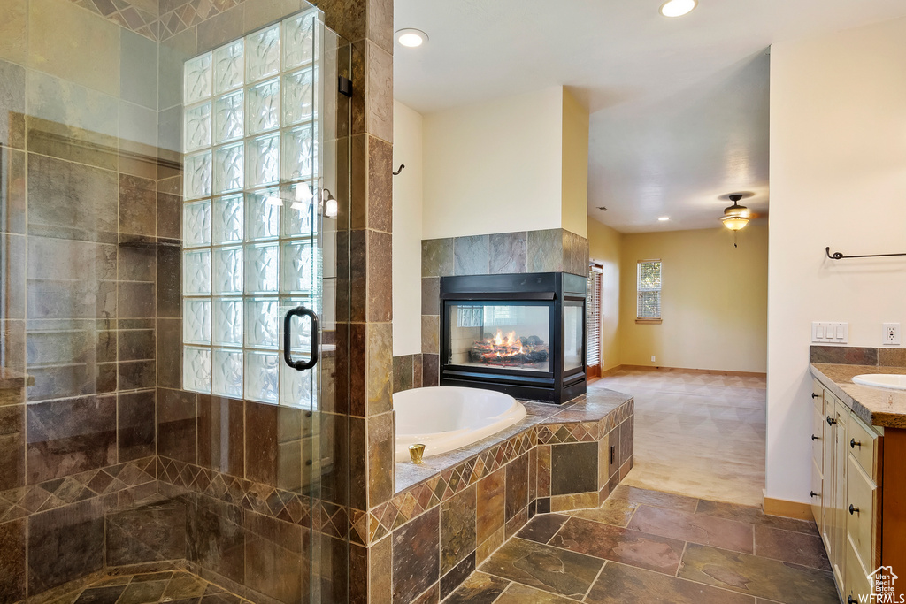 Bathroom featuring vanity, a fireplace, independent shower and bath, tile flooring, and ceiling fan