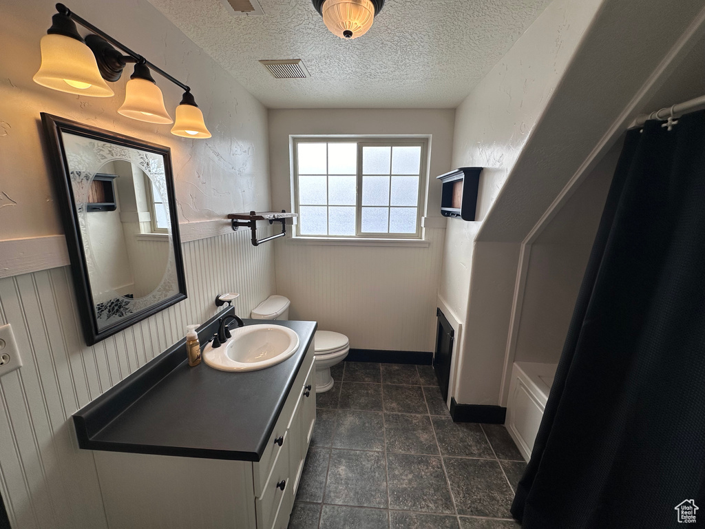 Full bathroom featuring a textured ceiling, toilet, shower / bath combination with curtain, tile floors, and oversized vanity